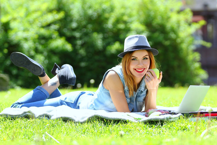 happy woman eating an apply in a park
